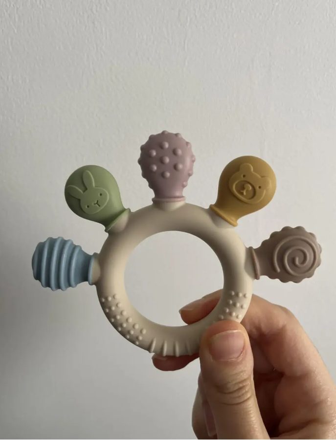 Anneau de dentition pour bébé en silicone avec différentes textures, idéal pour soulager les gencives lors des poussées dentaires.