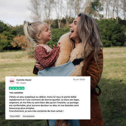 Cliente portant son enfant en porte-bébé ergonomique HelloBiboo lors d’une promenade en extérieur