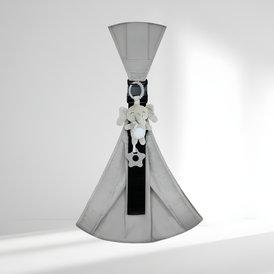 Doudou de dentition éléphant HelloBiboo accroché à un porte-bébé gris pour apaiser les gencives de bébé