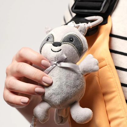 Doudou raton laveur gris attaché sur un porte-bébé, tenu à la main pendant le portage pour rassurer bébé