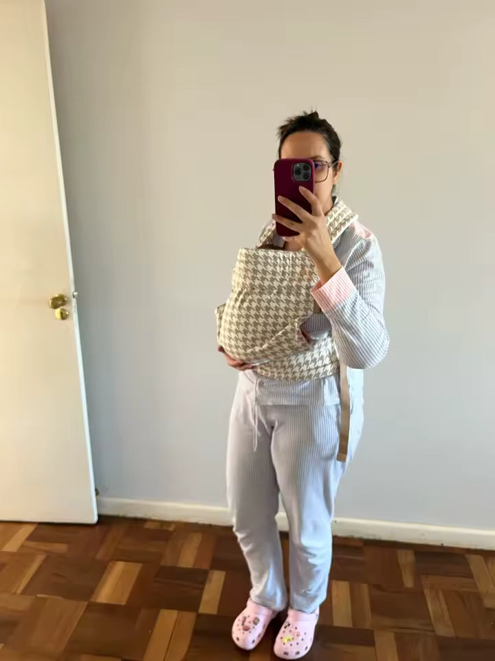 Maman portant son bébé dans le porte-bébé HelloBiboo à la maison, portage confortable et bébé bien maintenu contre elle.