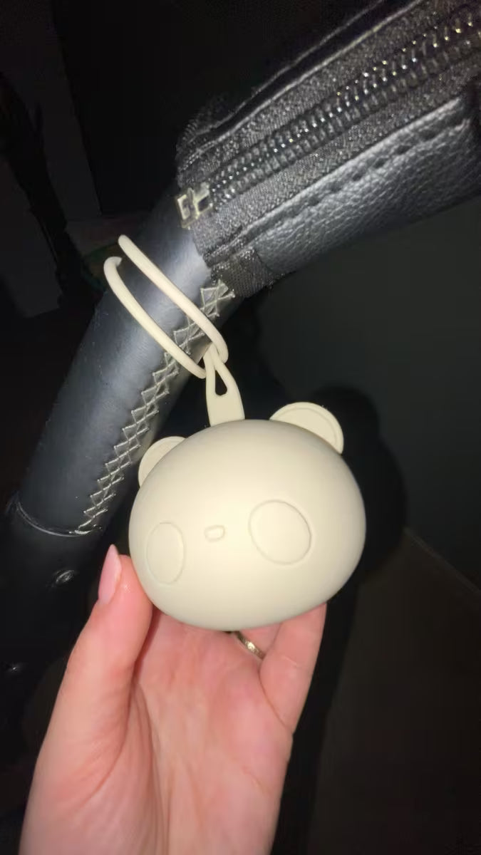 Porte-tétine pour bébé en silicone accroché à une poussette, solution pratique et hygiénique pour transporter la tétine en sortie.