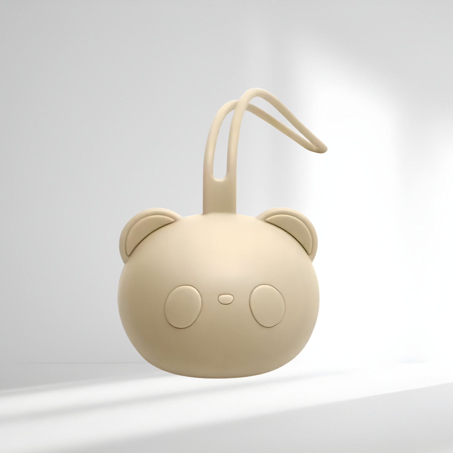 Porte-tétine en silicone beige en forme d’ourson, présenté sur un fond lumineux