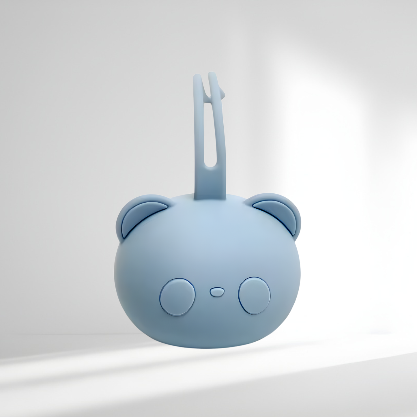 Porte-tétine en silicone bleu clair en forme d’ourson, présenté sur un fond lumineux