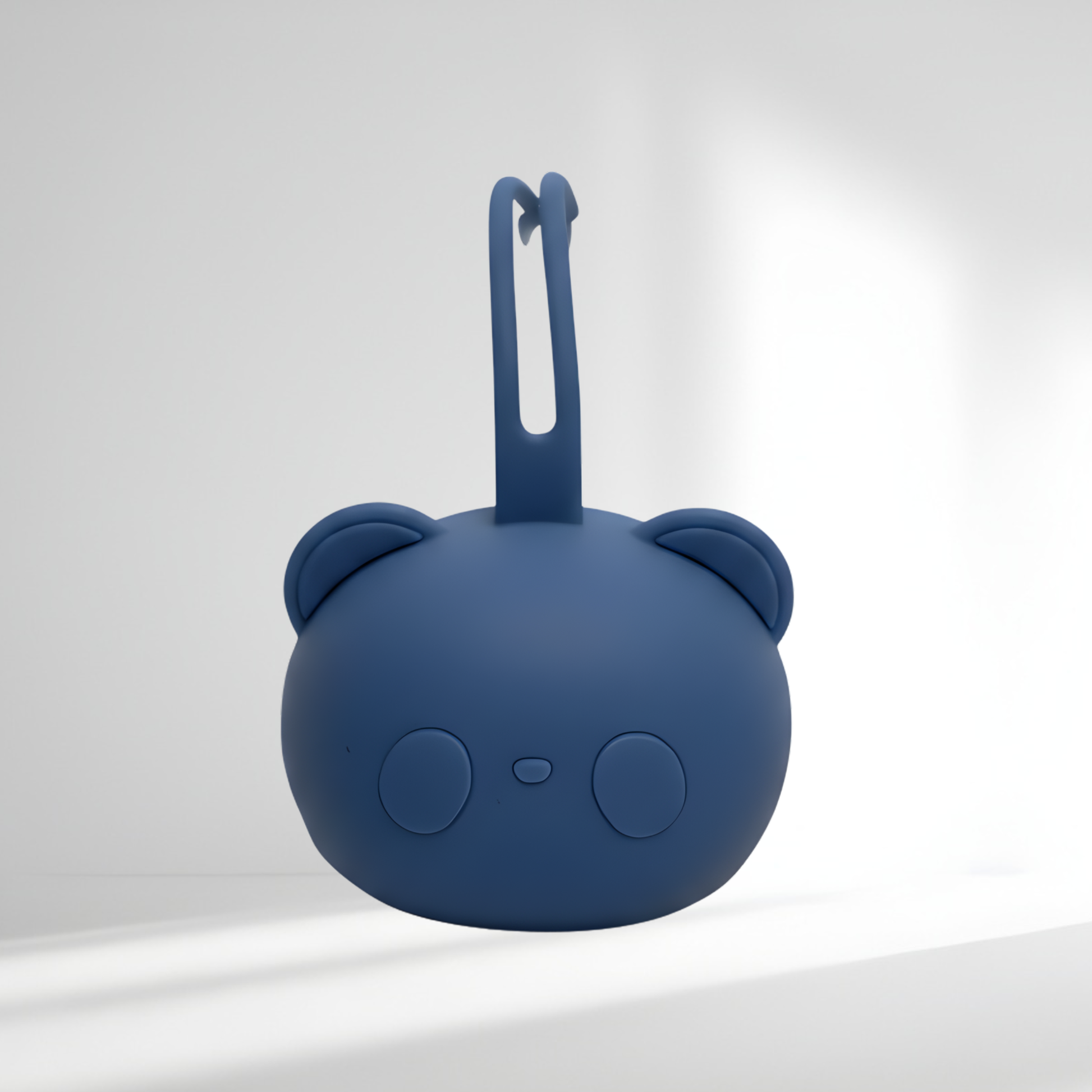 Porte-tétine en silicone bleu marine en forme d’ourson, présenté sur un fond lumineux