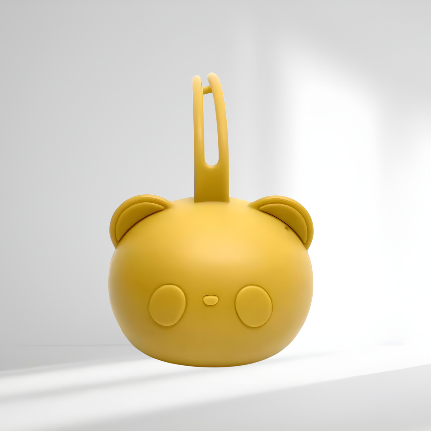 Porte-tétine en silicone jaune en forme d’ourson, présenté sur un fond lumineux