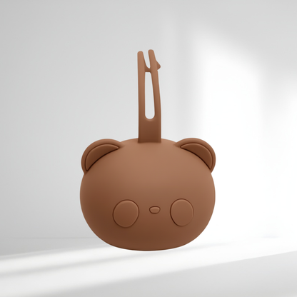 Porte-tétine en silicone marron en forme d’ourson, présenté sur un fond lumineux
