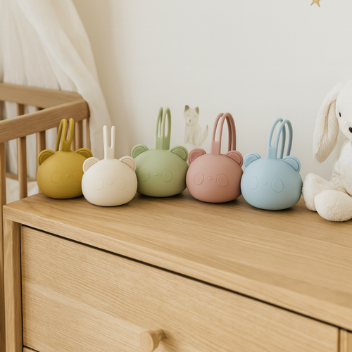 Porte-tétines en silicone de différentes couleurs posés sur une commode dans une chambre de bébé